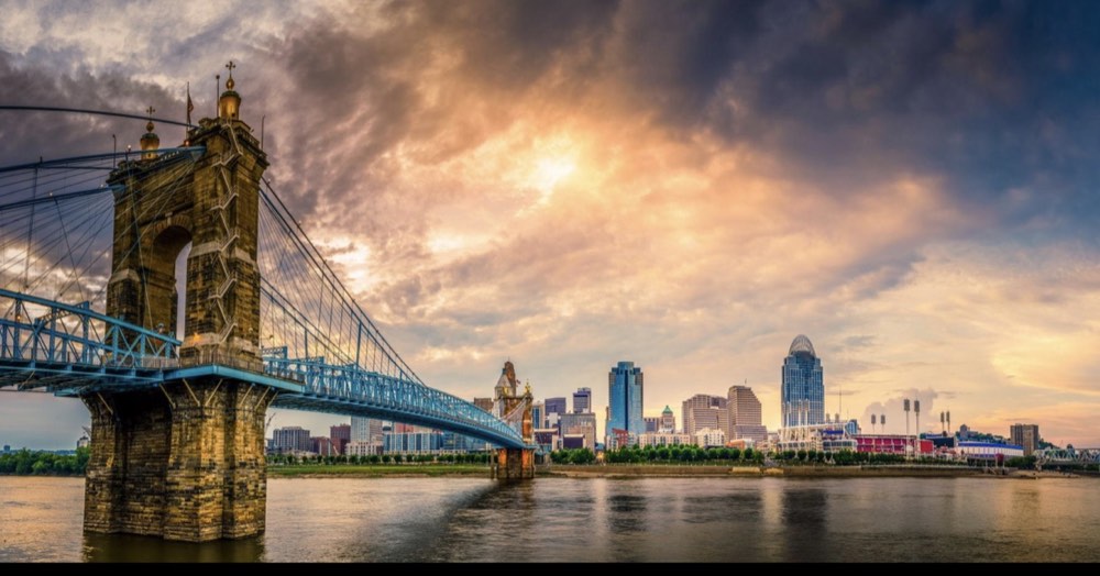 The Cincinnati skyline and the Roebling Suspension Bridge over the Ohio River at sunset.